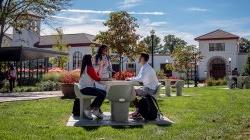 three students seated at outdoor table on Montclair campus