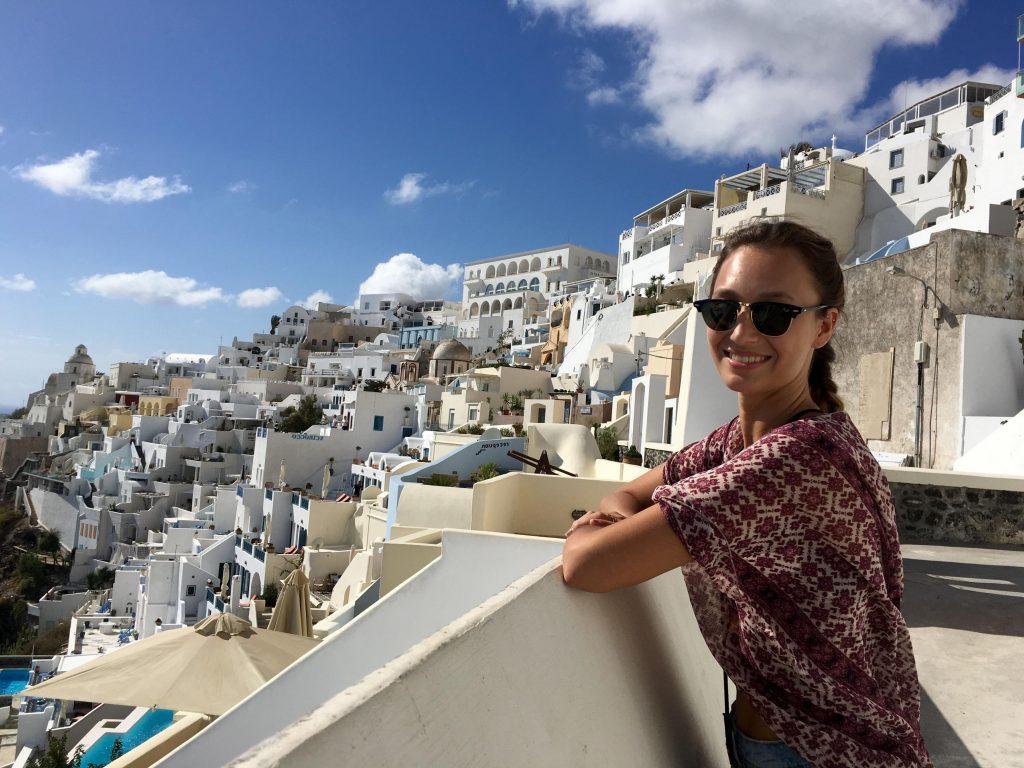 Student posing on balcony in Grecian cliffside town